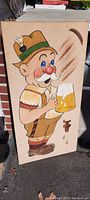 Full front view of the vintage corkboard sign showing cartoon beer drinker character