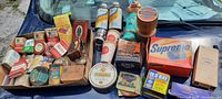 Full overview of the assortment of vintage product packages including spice tins, tobacco tins, automotive kits, and collectible Coca-Cola items.