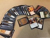 Several Magic the Gathering cards arranged fanned out showing fronts and backs, featuring different character and creature artwork.