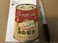 Front cover of tiny promotional recipe book shaped like Campbell's Condensed Tomato Soup can with label 'Made in Canada'. Marker placed for scale.