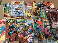 Photo showing a spread of 12 comic books with visible titles including Batman, Superman, WildC.A.T.s, Hawk and Dove, Mighty Marvel, and Archie comics.
