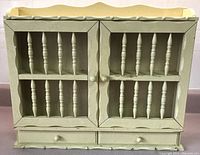 Front view of vintage butter yellow wooden spice rack with two spindled glass doors and two drawers