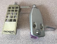 Thorens lattice design headshell on the left and silver Pioneer headshell with visible purple stylus on the right on carpeted surface