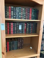 Full bookshelf with three shelves of leatherbound volumes