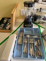 Photo showing Hamilton Beach blender, cutting tool, wooden flatware box, and blue plastic flatware tray on a kitchen counter
