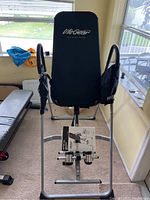 Front view of the Life Gear inversion table showing black padded backrest and silver frame with attached user manual.