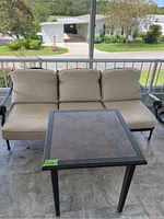 Patio sofa with beige cushions positioned behind small metal table with stone top, showing overall lot contents and outdoor setting.