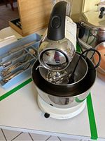 Front view focusing on the mixer head attachment and stainless steel bowl with beaters inside.