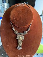 Full view of the silver-tone antique costume jewelry necklace displayed on a brown velvet stand.