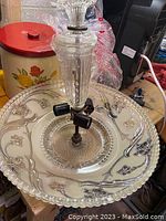 Top view of large glass ceiling shade with floral embossed motifs and black metal light sockets on clear glass stem.