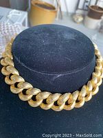 Front view of the chunky Les Bernard INC large chain choker necklace on a black display stand, showing a gold-tone textured finish.