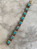 Full length view of bracelet showing turquoise stone inlay and linked rectangular segments.