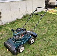 Left side view of Craftsman yard vacuum with black handle, white wheels, green engine cover and chipper chute on side.