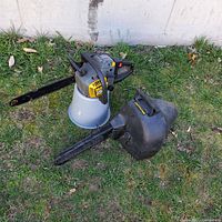 McCulloch MAC3516 chainsaw with case placed on grass against a white wall. Chainsaw shows yellow and gray color with a black chain bar. Black plastic carrying case beside chainsaw.