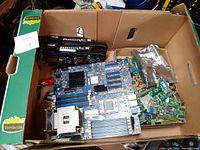 Box containing various computer parts: motherboards, RAM, expansion cards, laptop panels