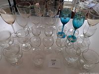 Full assortment of stemware glassware arranged on table showcasing a variety of sizes and styles including clear and blue tinted glasses.