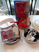 Photo showing assortment of baking and cooking items including divided casserole dish, silicone molds, measuring utensils, wooden sticks, and hot chocolate bomb mold.