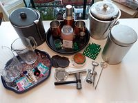 Photo showing the complete set, including two ice buckets, glass jugs, cocktail shaker, cups, bar tools and bottle stoppers on trays
