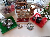 Overall collection of assorted candle holders, candles, potpourri pots and decorative items placed on bright green and red trays