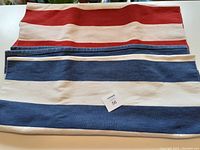 Two Ikea flat woven runners, one red stripe and one blue stripe, laid side by side on a flat surface.