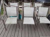 Front view of all six outdoor dining chairs arranged in two rows showing metal frames with armrests and light gray woven mesh seats and backs.