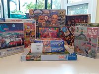 Photo showing the full assortment of puzzles including 'Pick Me Up Puzzle,' 'Candy Wrappers,' and other vintage and colorful themed puzzles