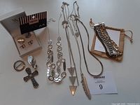 Overview photo showing multiple silver tone jewelry pieces including necklaces, earrings, a ring, and bracelets in pouch.
