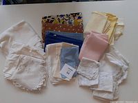 Overview photo of assorted linen napkins, placemats, and tablecloths in various colors and patterns displayed on a table.