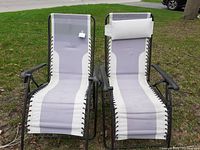 Photo of two gray zero gravity recliner chairs on grass, showing fabric with light and dark gray color blocks and black metal frames with bungee cord attachments.