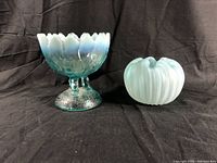 Both blue glass bowls side by side on black fabric background illustrating size, shape, and color differences