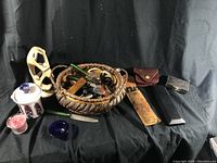 Wide view of all items on black background showing basket, carved figurine, ceramic jar, candles and several other accessories.
