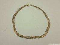 Full view of the braided multi-toned chain necklace showing intertwined gold, rose gold, and silver toned links with textured finish.
