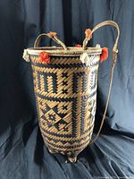 Front angled view of the woven basket highlighting the geometric pattern and braided handles with red and white adornments.