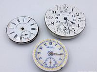 Three vintage mechanical pocket watch faces showing the Waltham, Corona Chronometre, and Nassau faces with varying numeral styles and subdials.