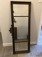 Full view of the mirror standing upright, showing the entire reflective surface and frame details.