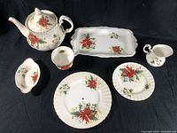 Tea service arranged on black background showing teapot, rectangular tray, creamer, oval dish, round plate and saucer
