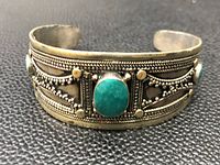 Front view of vintage silver turquoise cuff bracelet showing central oval turquoise and intricate silver bead and rope design.