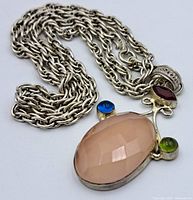 Photo showing the full necklace and pendant with the oval peach/pink stone and the chain detail.