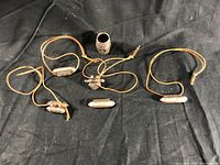 Four silver pendants on brown leather cords with one broad silver engraved ring placed at center on black background.