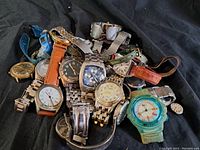Photo of a pile of vintage wristwatches with assorted band materials and dial colors showing general lot condition