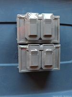 Top view of two gray weather resistant outdoor Leviton duplex receptacles with flip covers, still wrapped in plastic.