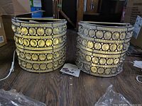 Two cylindrical crystal and silver metal wall sconces with plug cords on wooden floor
