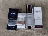Four skincare products in original packaging arranged side by side on a concrete background, showing front labels.