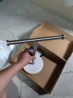 Twin towel holder with a horizontal stainless steel bar and vertical post, mounted on a circular white marble base