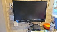 Vizio flat screen TV mounted on wall with remote and accessories below