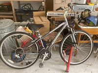 Full left-side view of silver hybrid bike showing frame, wheels, saddle and handlebars