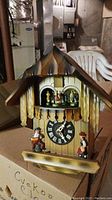 Full view of the cuckoo clock showing wooden chalet design with figurines and clock face.