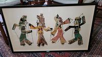 Framed set of four Chinese shadow puppets displayed on a cream backing with a simple black frame, showing entire lot.