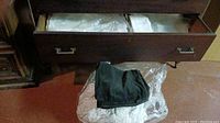 Drawer showing folded white table linen and plastic covering underneath.