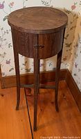 Front view of the wood round table showing the small door and latch with four legs.